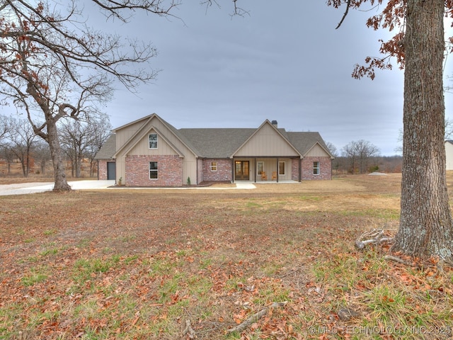 view of front facade featuring roof with shingles, brick siding, and a front lawn