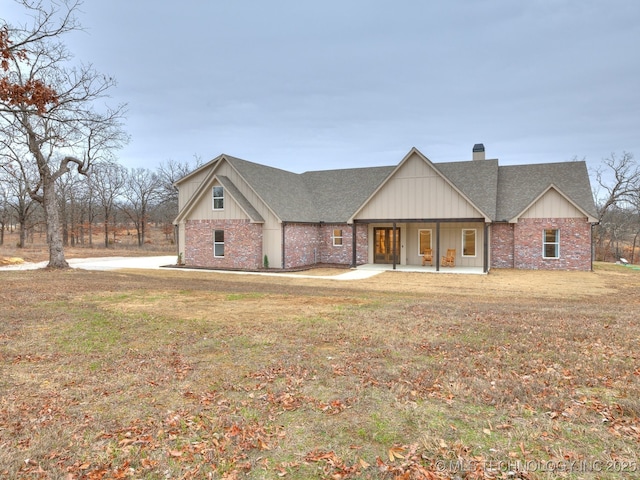 modern inspired farmhouse featuring a front yard, brick siding, and a chimney