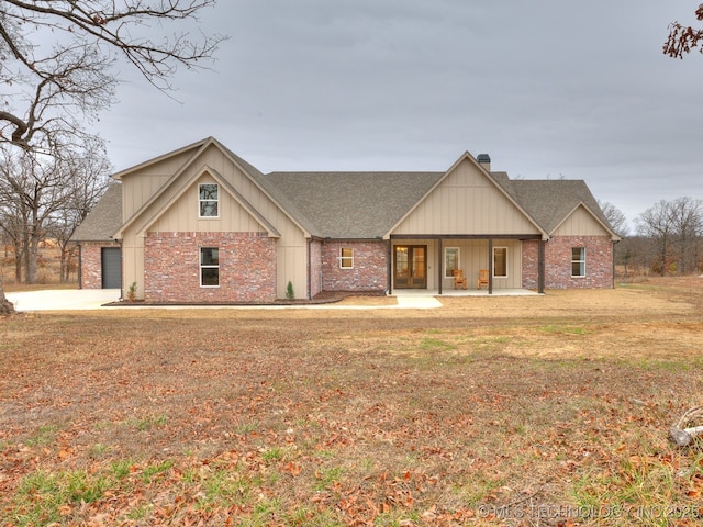 view of front of house with a porch, brick siding, a shingled roof, and a front lawn