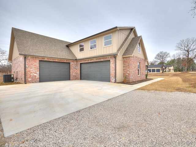 traditional home featuring central air condition unit, a garage, brick siding, concrete driveway, and roof with shingles