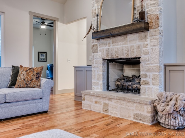 living room with a fireplace, baseboards, and wood finished floors