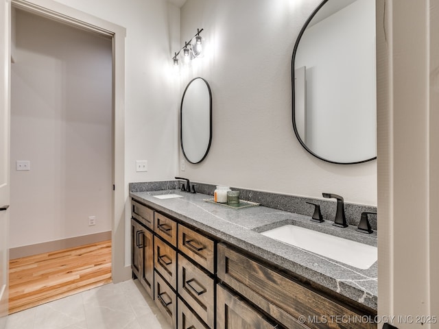 full bathroom featuring double vanity, baseboards, and a sink