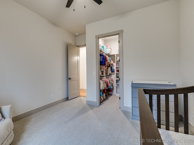 bedroom with a closet, light colored carpet, a spacious closet, and baseboards