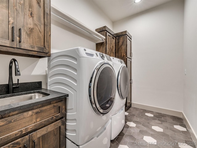 laundry room featuring cabinet space, baseboards, separate washer and dryer, and a sink