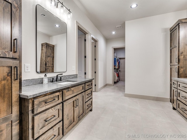 bathroom featuring a walk in closet, recessed lighting, visible vents, vanity, and baseboards