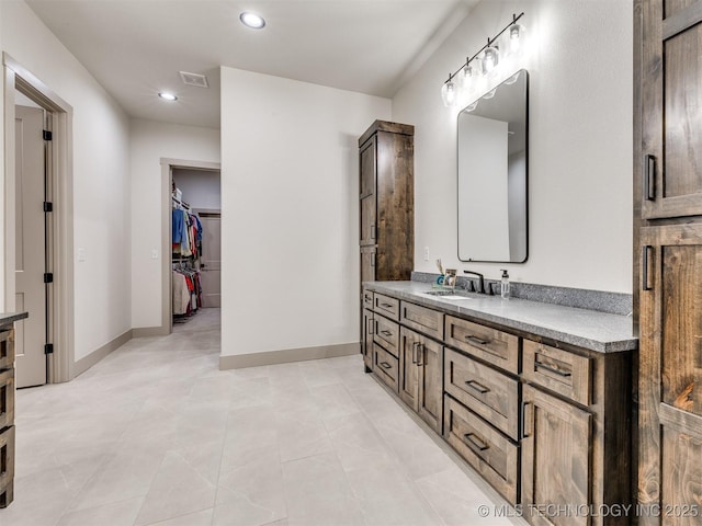 bathroom with baseboards, visible vents, a spacious closet, vanity, and recessed lighting