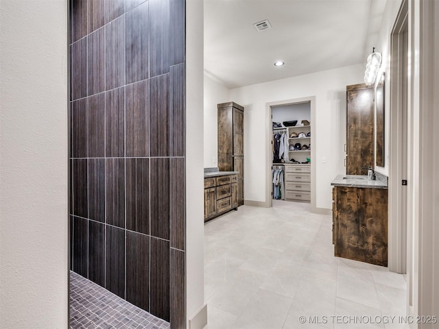 full bathroom featuring visible vents, tile patterned flooring, walk in shower, a walk in closet, and vanity