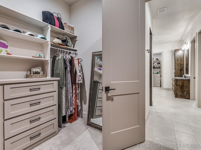 walk in closet with light tile patterned floors, visible vents, and a sink