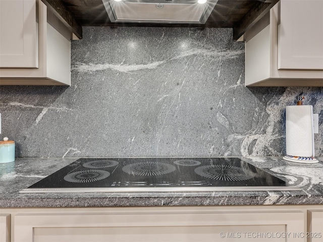 details with tasteful backsplash, dark stone countertops, wall chimney range hood, and black electric stovetop