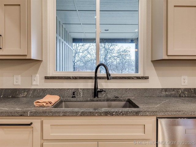 kitchen with dark countertops, a sink, and white cabinets