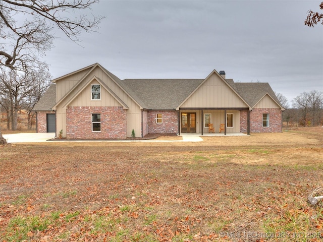 view of front of home featuring a shingled roof, brick siding, a chimney, and a front lawn