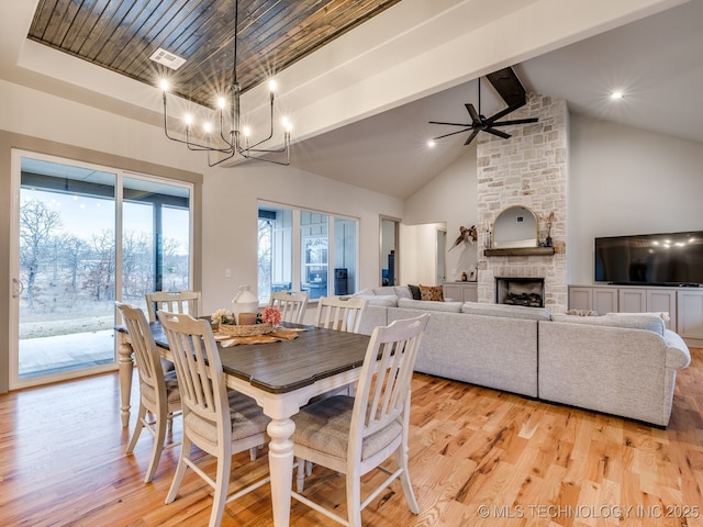 dining area with a large fireplace, high vaulted ceiling, light wood finished floors, and beamed ceiling