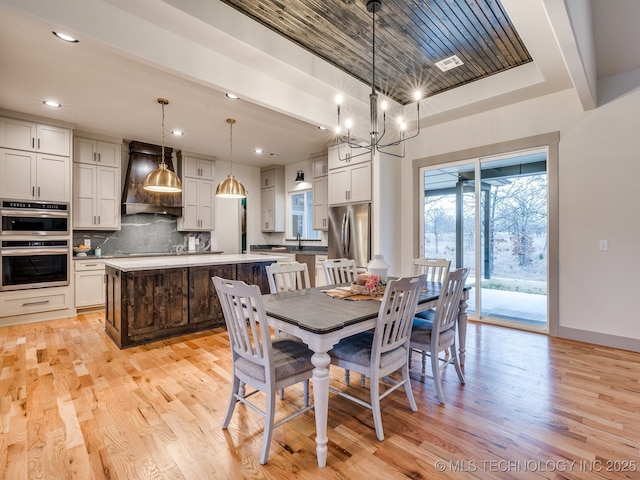 dining area featuring light wood-type flooring, baseboards, a tray ceiling, and recessed lighting