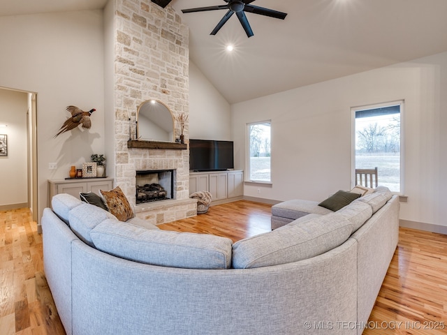 living room with light wood-style floors, a fireplace, and high vaulted ceiling