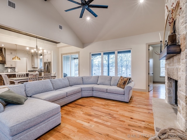 living room with light wood finished floors, a fireplace, visible vents, and high vaulted ceiling