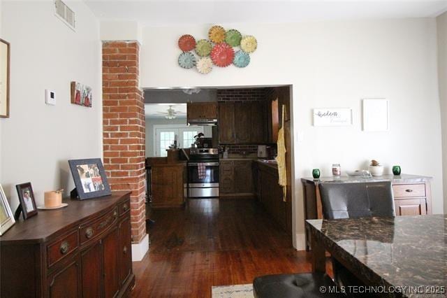 kitchen with under cabinet range hood, visible vents, stainless steel electric range, dark stone countertops, and dark wood finished floors