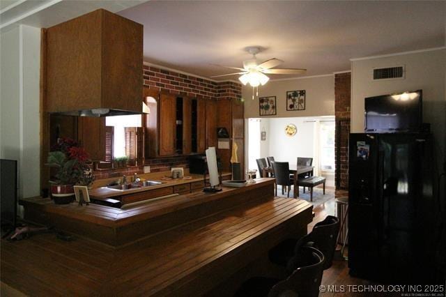 interior space with ceiling fan, brown cabinetry, a sink, and visible vents