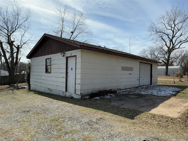 view of outdoor structure featuring driveway, fence, and an outdoor structure