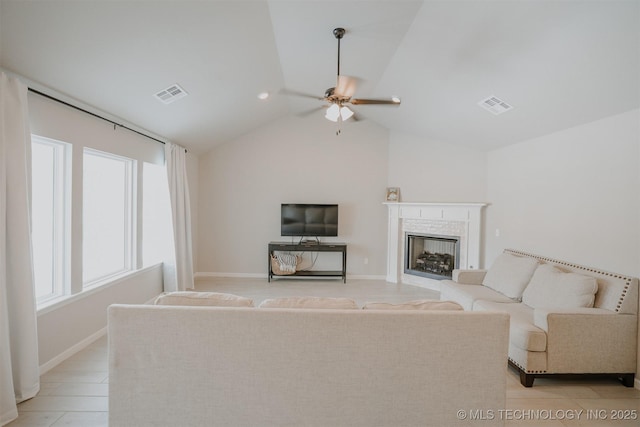 living room featuring lofted ceiling, a fireplace, visible vents, and a ceiling fan