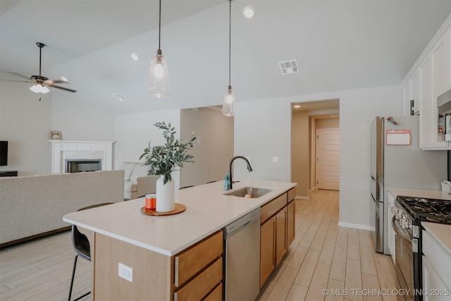 kitchen featuring visible vents, appliances with stainless steel finishes, open floor plan, white cabinets, and a sink