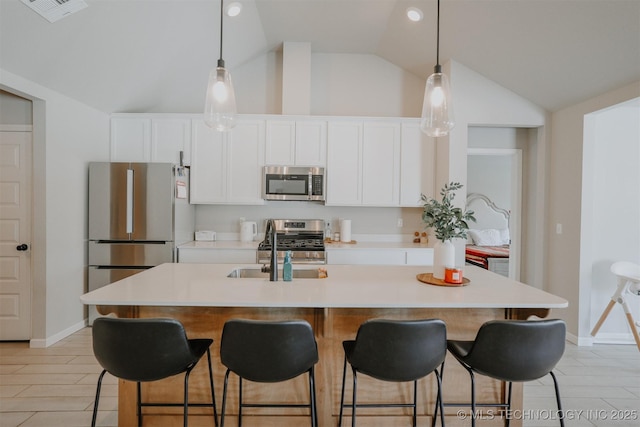 kitchen featuring a kitchen island with sink, stainless steel appliances, visible vents, white cabinets, and light countertops