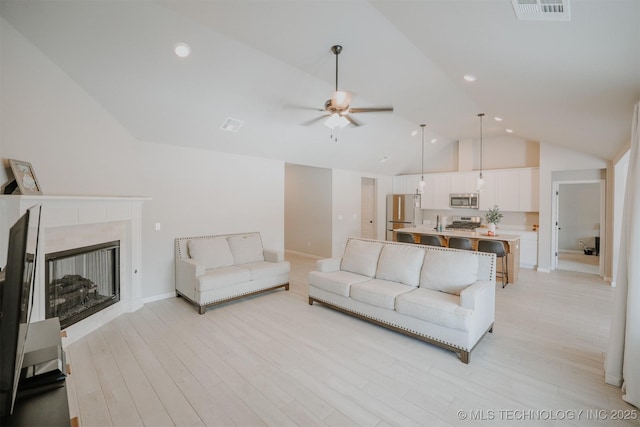 living area with light wood-style floors, a ceiling fan, visible vents, and a premium fireplace