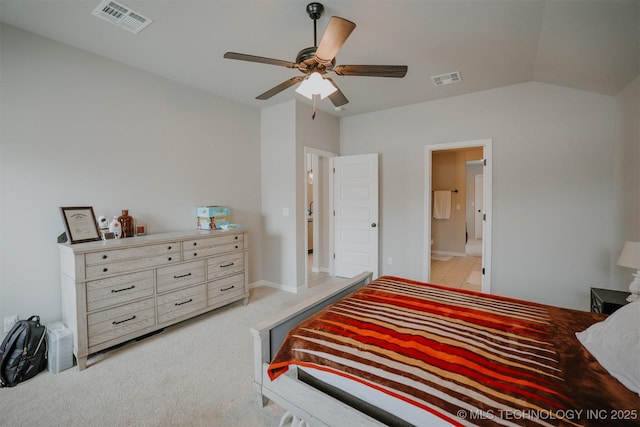 bedroom with vaulted ceiling, light carpet, visible vents, and ensuite bathroom