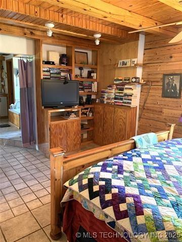 bedroom featuring beam ceiling, wood walls, light tile patterned flooring, and wood ceiling