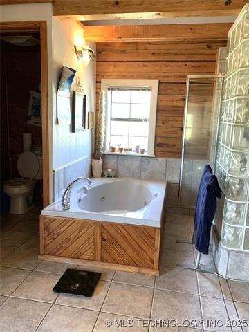 full bath with toilet, wooden walls, beam ceiling, and tile patterned floors