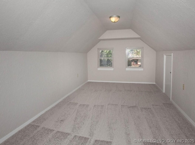 bonus room with lofted ceiling, light carpet, a textured ceiling, and baseboards