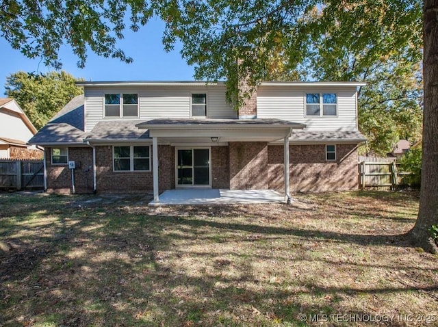 back of property featuring brick siding, a yard, fence, and a patio