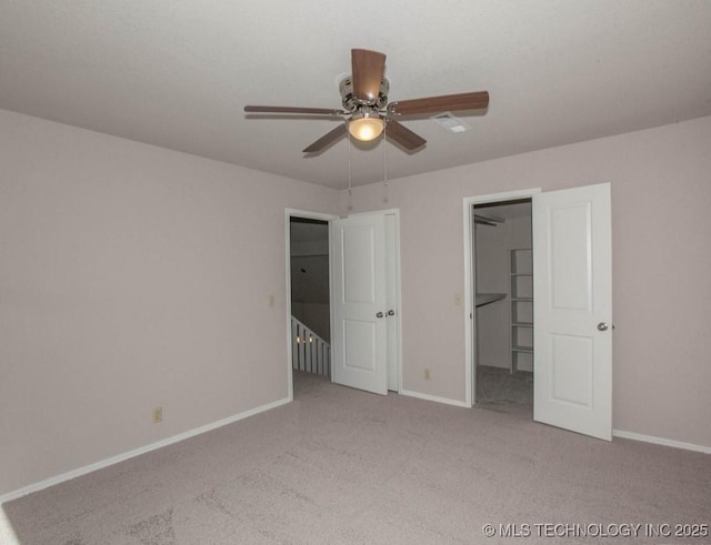 unfurnished bedroom with a walk in closet, light carpet, ceiling fan, and baseboards