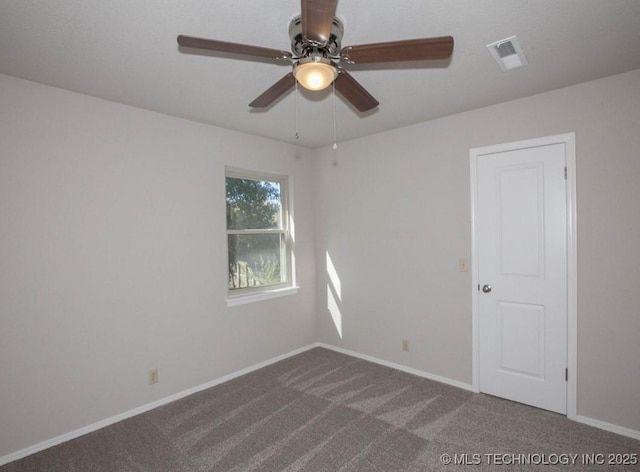 carpeted spare room with a ceiling fan, visible vents, and baseboards