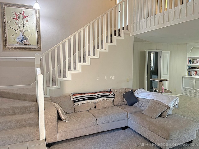 carpeted living area with stairway and a towering ceiling