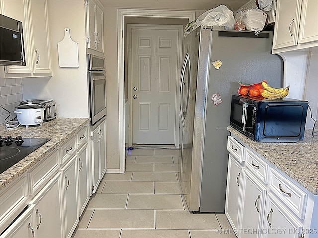 kitchen featuring white cabinetry, stainless steel oven, light stone counters, and light tile patterned flooring