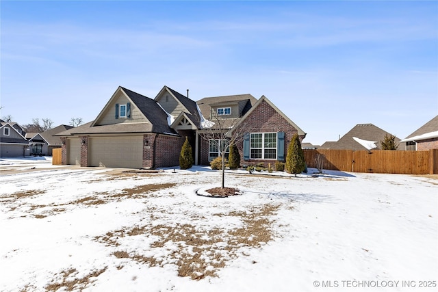 view of front of home with a garage, brick siding, and fence