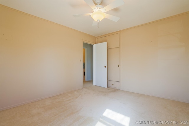 spare room featuring baseboards, a ceiling fan, and light colored carpet