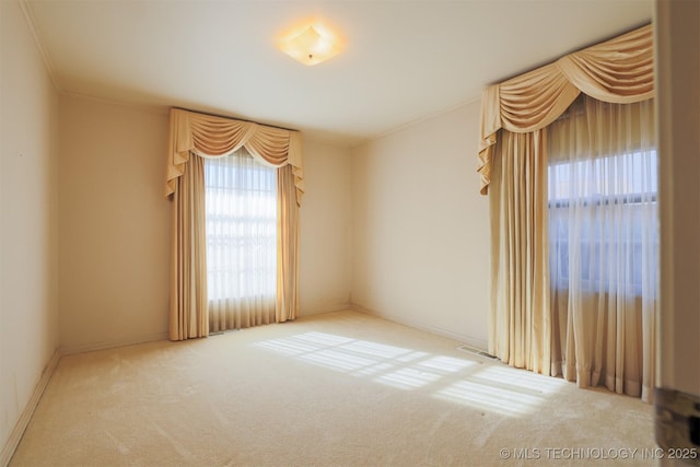 empty room featuring carpet flooring, visible vents, and ornamental molding