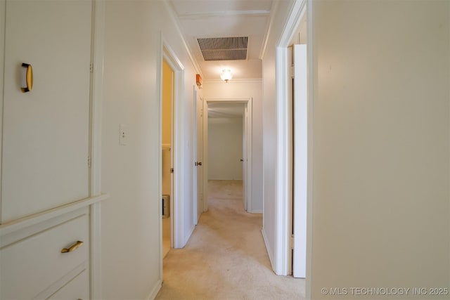 corridor with light colored carpet, visible vents, and baseboards