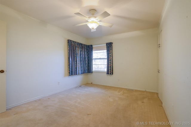 spare room featuring carpet flooring, baseboards, ornamental molding, and a ceiling fan