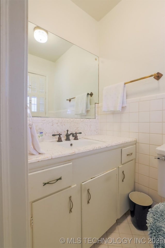 bathroom with tile walls, tile patterned flooring, vanity, and wainscoting