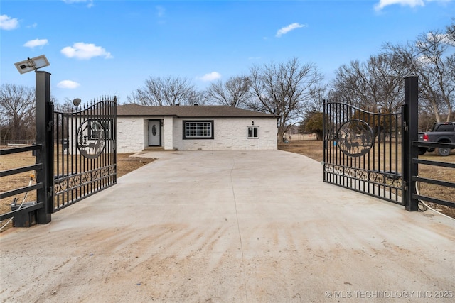 view of front facade featuring driveway, stone siding, a gate, and fence