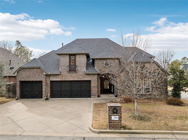 french country style house with a garage, concrete driveway, a shingled roof, and brick siding