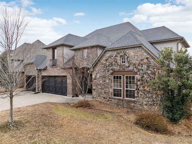 french country home featuring concrete driveway, a front lawn, roof with shingles, and stone siding