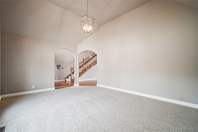 spare room with carpet floors, arched walkways, a notable chandelier, baseboards, and stairs