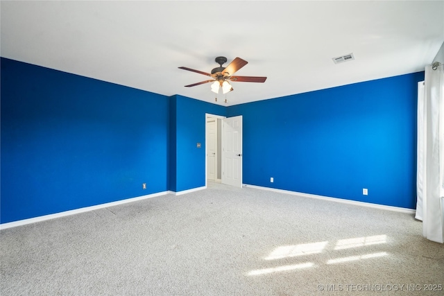 carpeted spare room with baseboards, visible vents, and ceiling fan