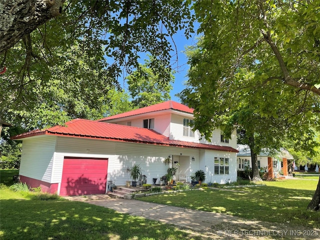 view of front facade with concrete driveway, metal roof, a front lawn, and an attached garage