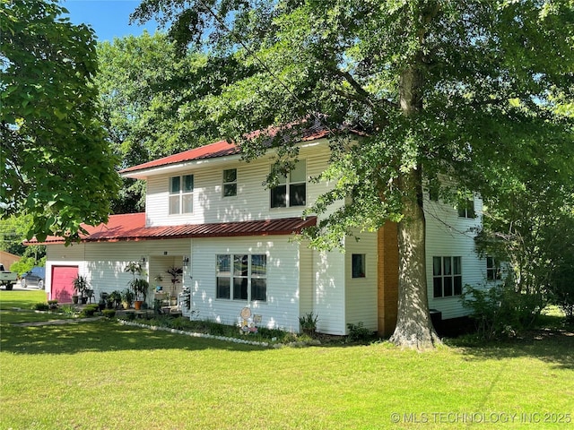 rear view of house with metal roof and a yard