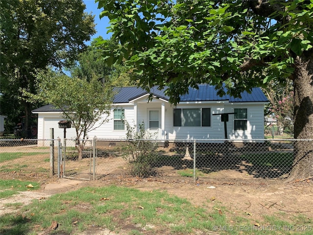 view of front facade featuring a fenced front yard, a gate, metal roof, and concrete driveway