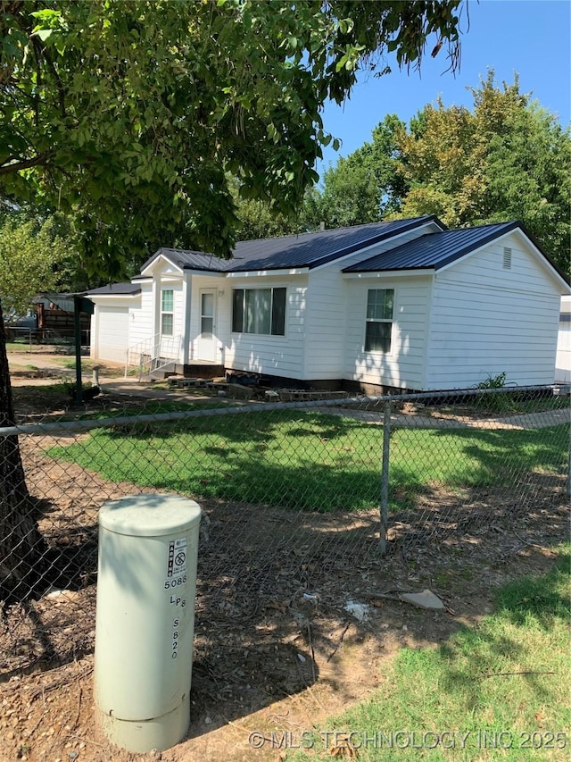 view of front of home featuring a front yard, metal roof, and fence